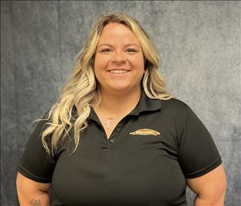 Female employee wearing black shirt standing in front of grey backdrop