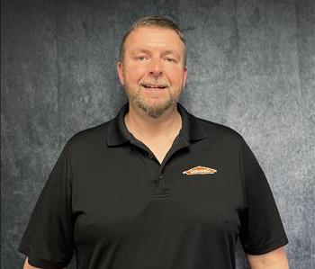 Tall male employee standing in front of grey backdrop