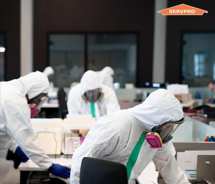 The image shows SERVPRO employees in hazmat suits sanitizing a facility